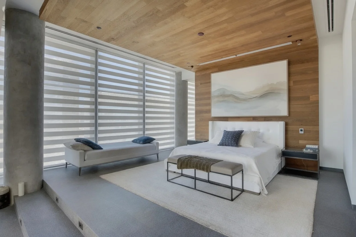 Zebra shades across full-height windows in a bedroom with warm wood finishes