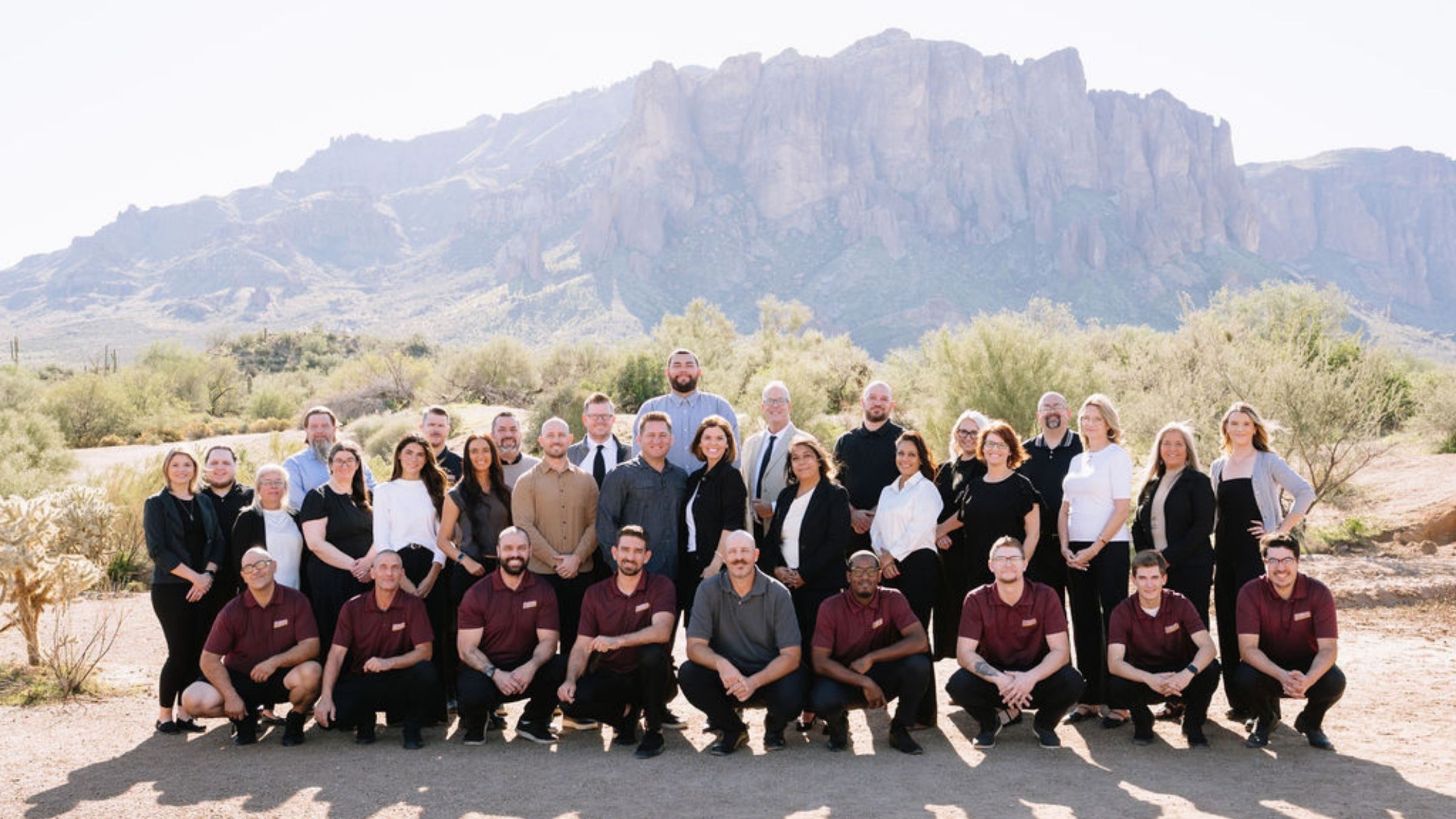 Team photograph of Southwest Blinds and Shutters employees standing in the Arizona desert with Superstition Mountain in the background